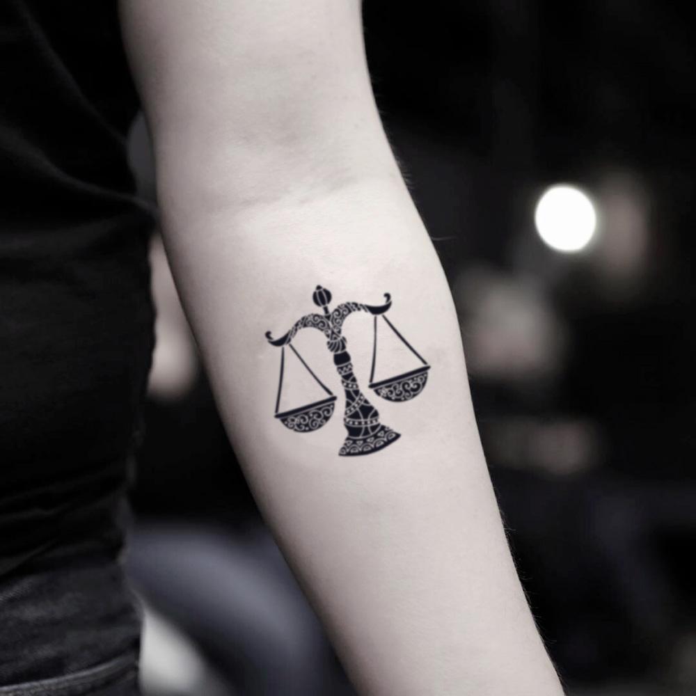 fake small libra sign balance scales of justice illustrative temporary tattoo sticker design idea on inner arm