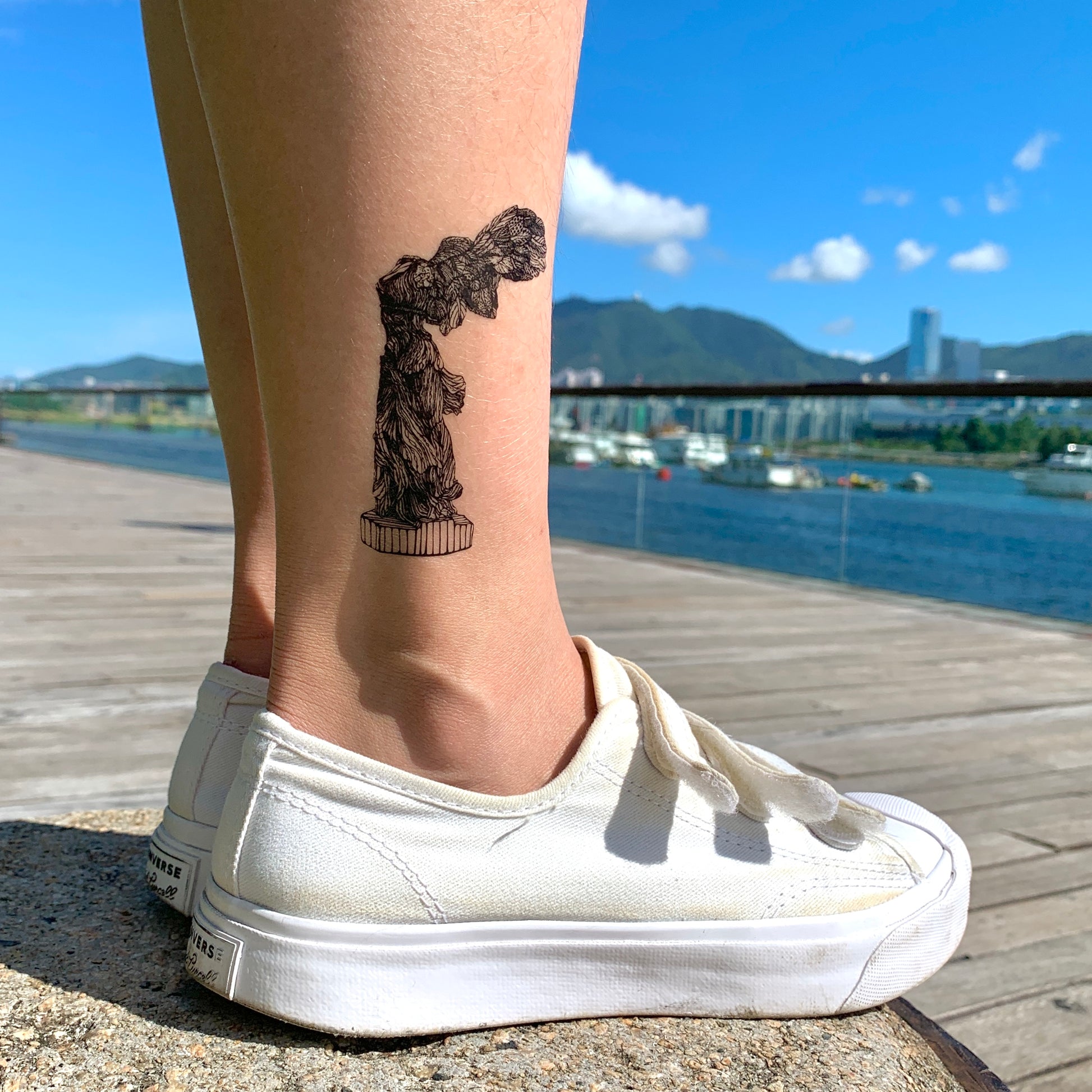 fake small winged victory of samothrace greek god goddess sculpture nike mythology angel statue illustrative temporary tattoo sticker design idea on leg ankle